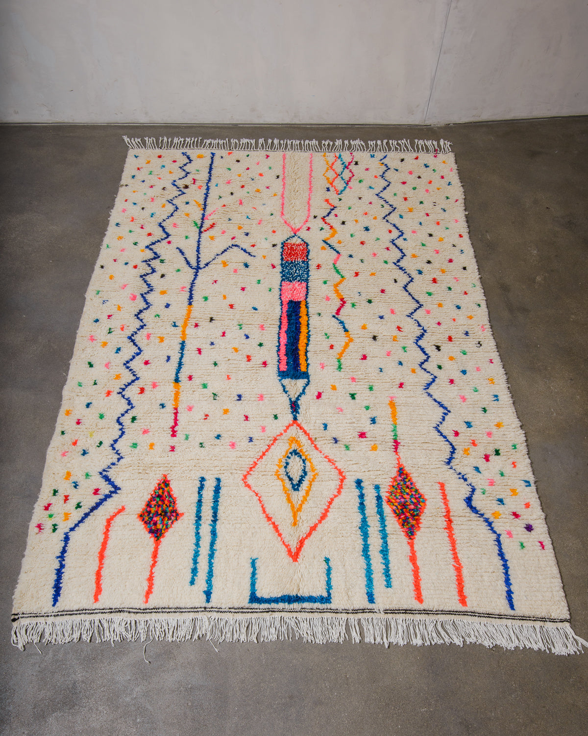 Berberlin Azilal rug made of fluffy wool and colourful cotton, laying flat on a concrete floor.